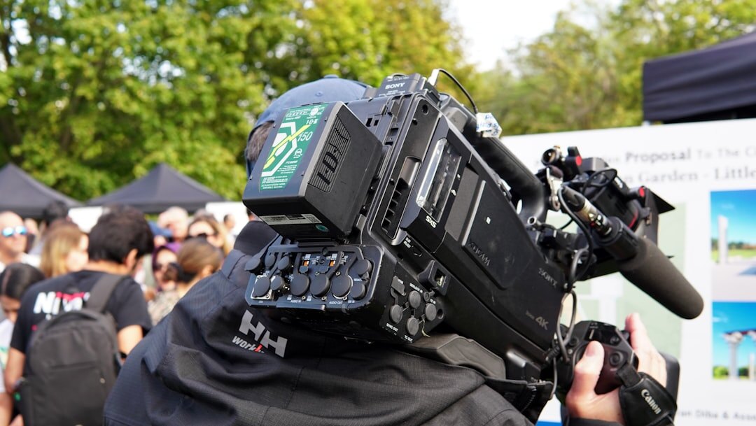 Field camera operator composing a live news shot outdoors