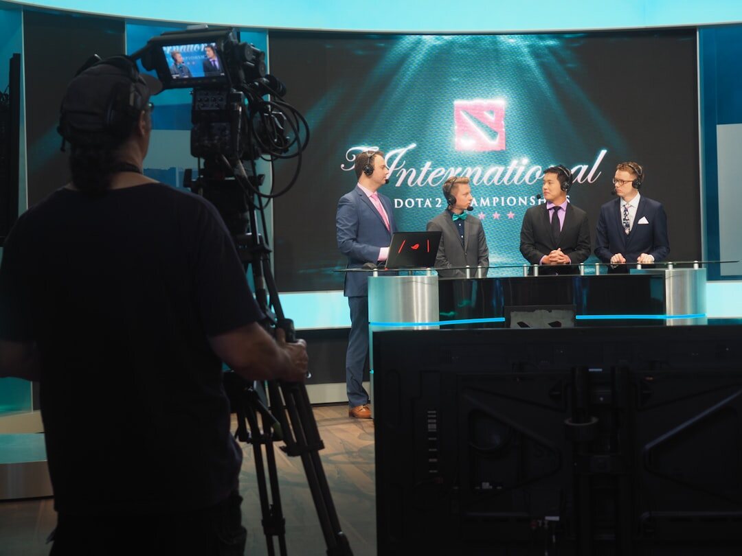 Camera operator framing a shot of a news presenter in a television studio